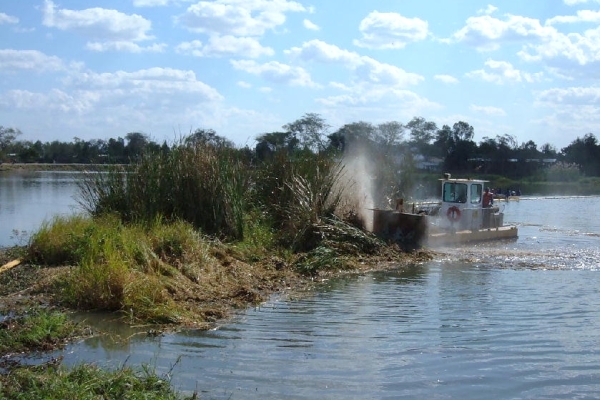 Chopping weed mats along the floating Boom in Malawi