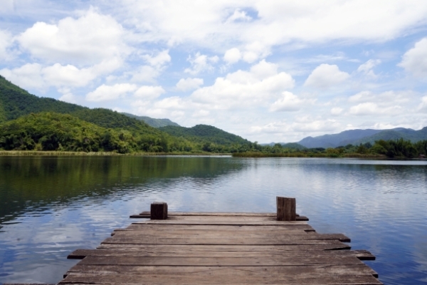 iStock-1326222924 Panoramic Wooden pier on lake in the mountain Wooden pier on lake in the mountain. Panoramic view of Wooden bridge lake with Green mountain, bright blue sky and lake at the background with Empty wooden floor.